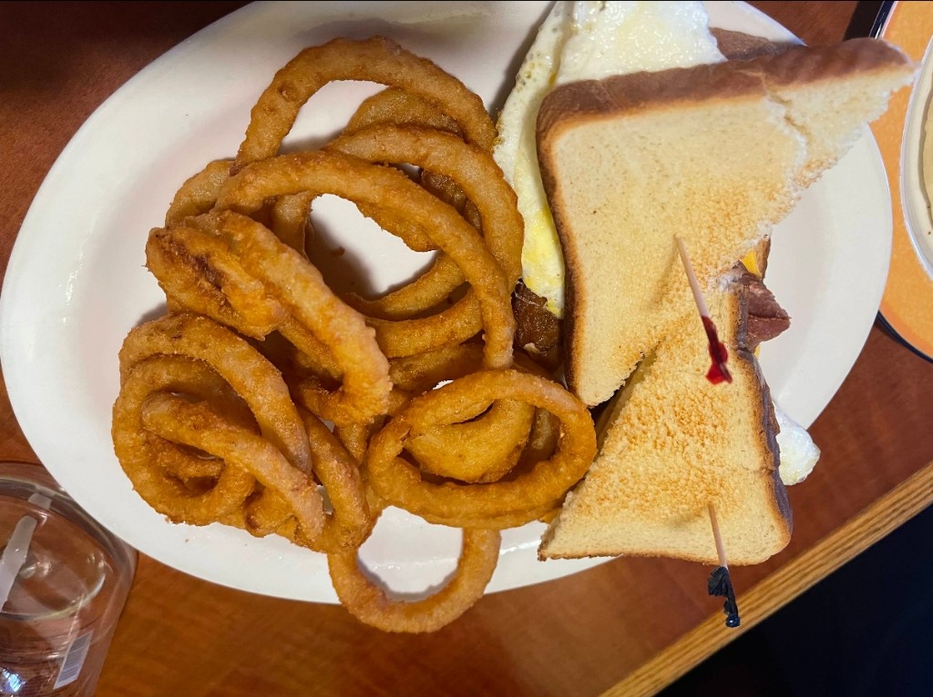 California club sandwich stacked tall with crispy golden onion rings